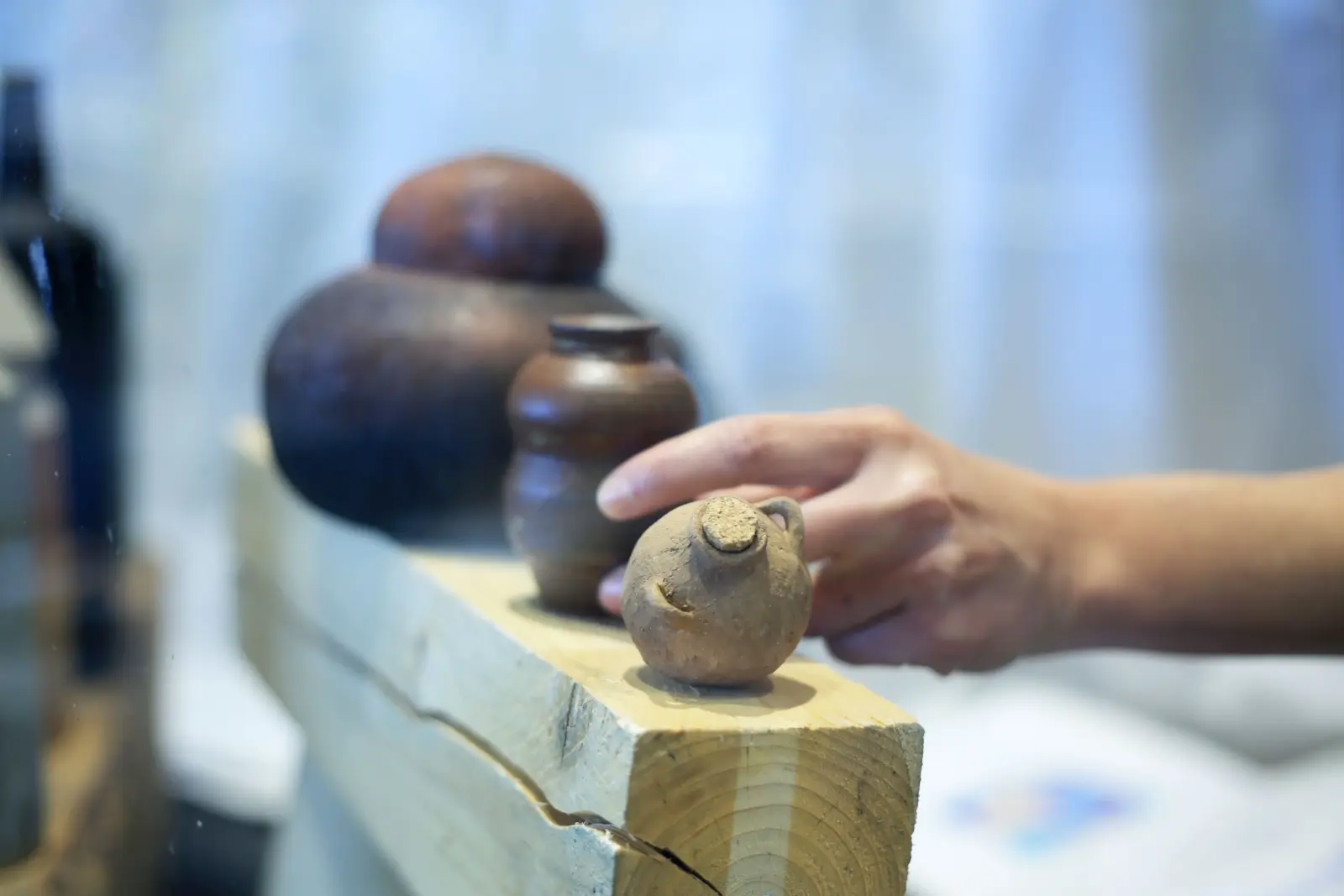 Main posant une pièce en céramique sur une étagère d'exposition