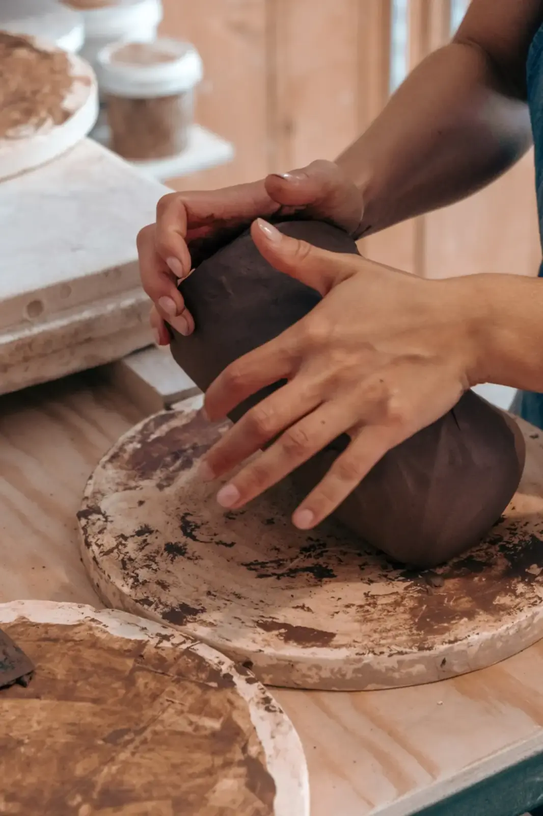 Mains modelant une pièce d'argile noire à l'atelier ZougZoug